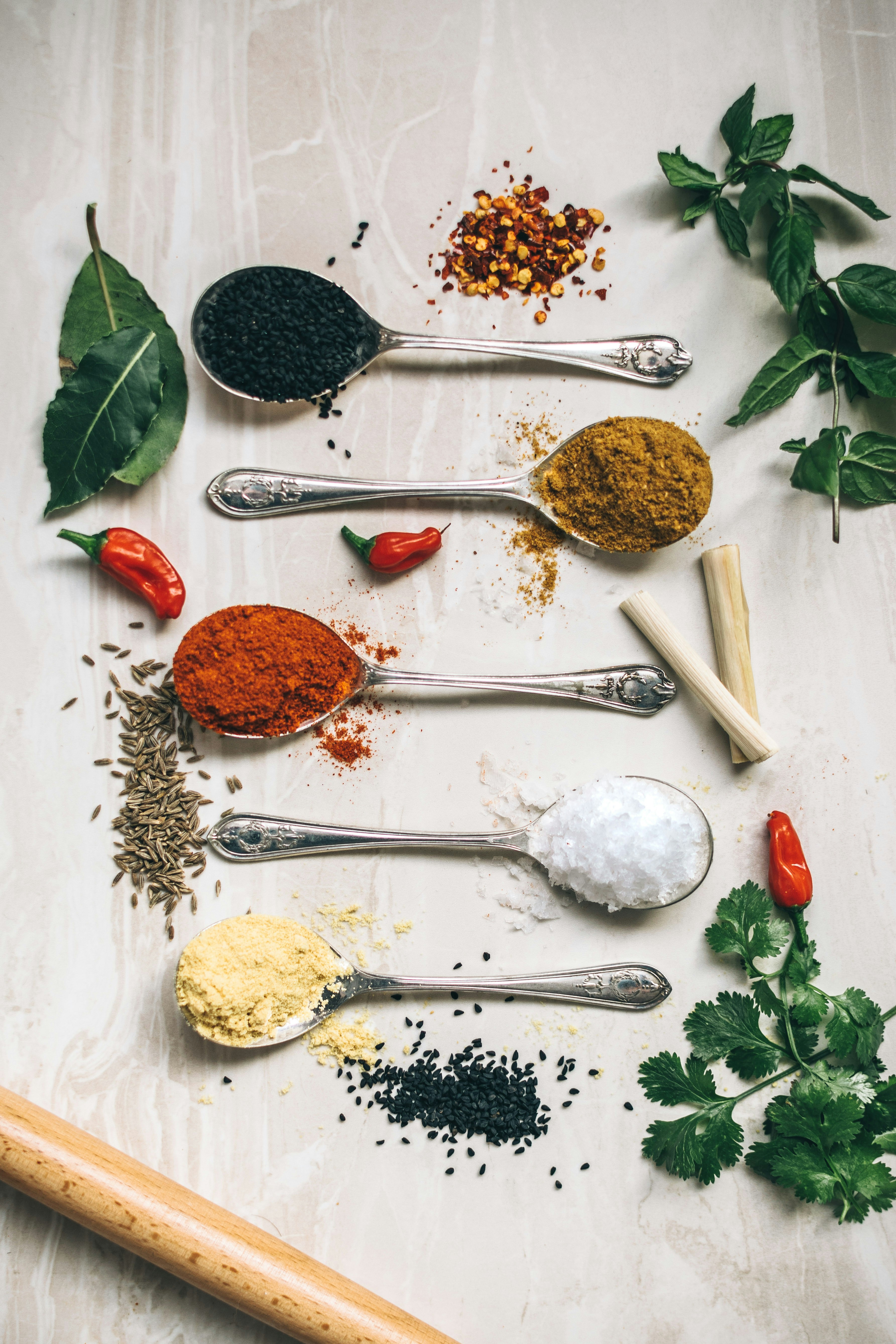Silver measuring spoons with colorful spices and dried herbs